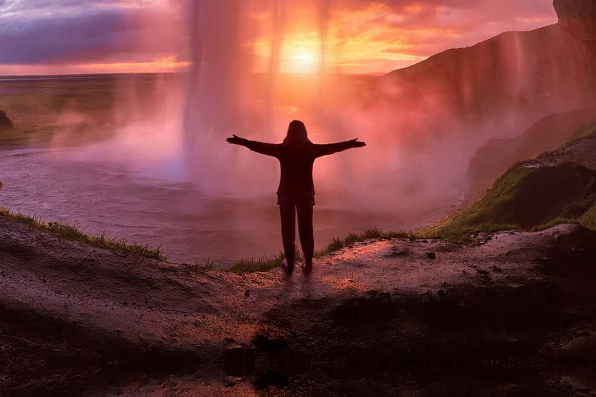 Smarte Anlagemöglichkeiten für Unternehmen Wanderin steht mit ausgebreiteten Händen vor einem Wasserfall