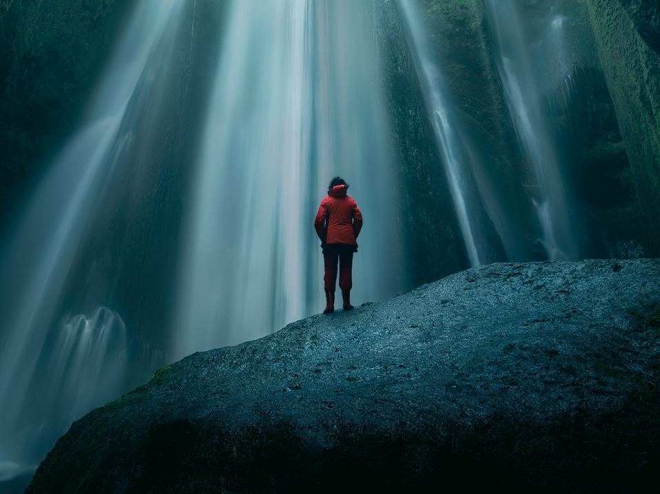 Person steht vor einem Wasserfall