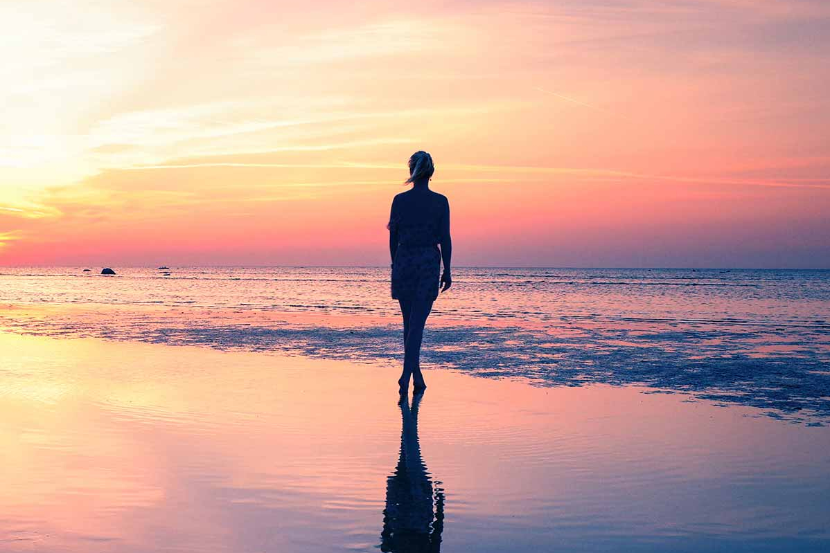 Arbeitszeit Depot Frau spaziert im seichten Teil des Meeres am Strand entlang